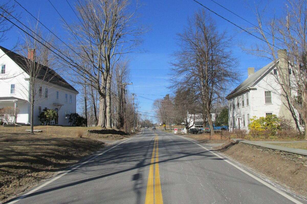 Historic white homes and tall trees along a quiet road in Atkinson NH