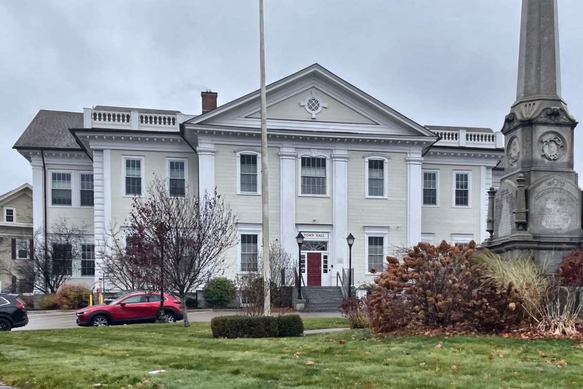 The white 1855 town hall and a stone war memorial on a fall day in Danvers MA