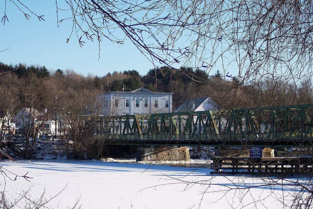 A green steel bridge over the frozen Merrimack River in Groveland MA