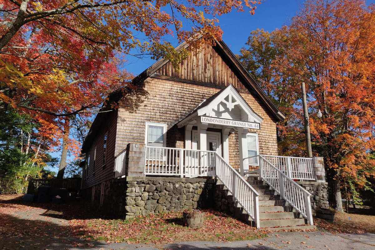 Shingled grange hall under fall maples in Londonderry NH