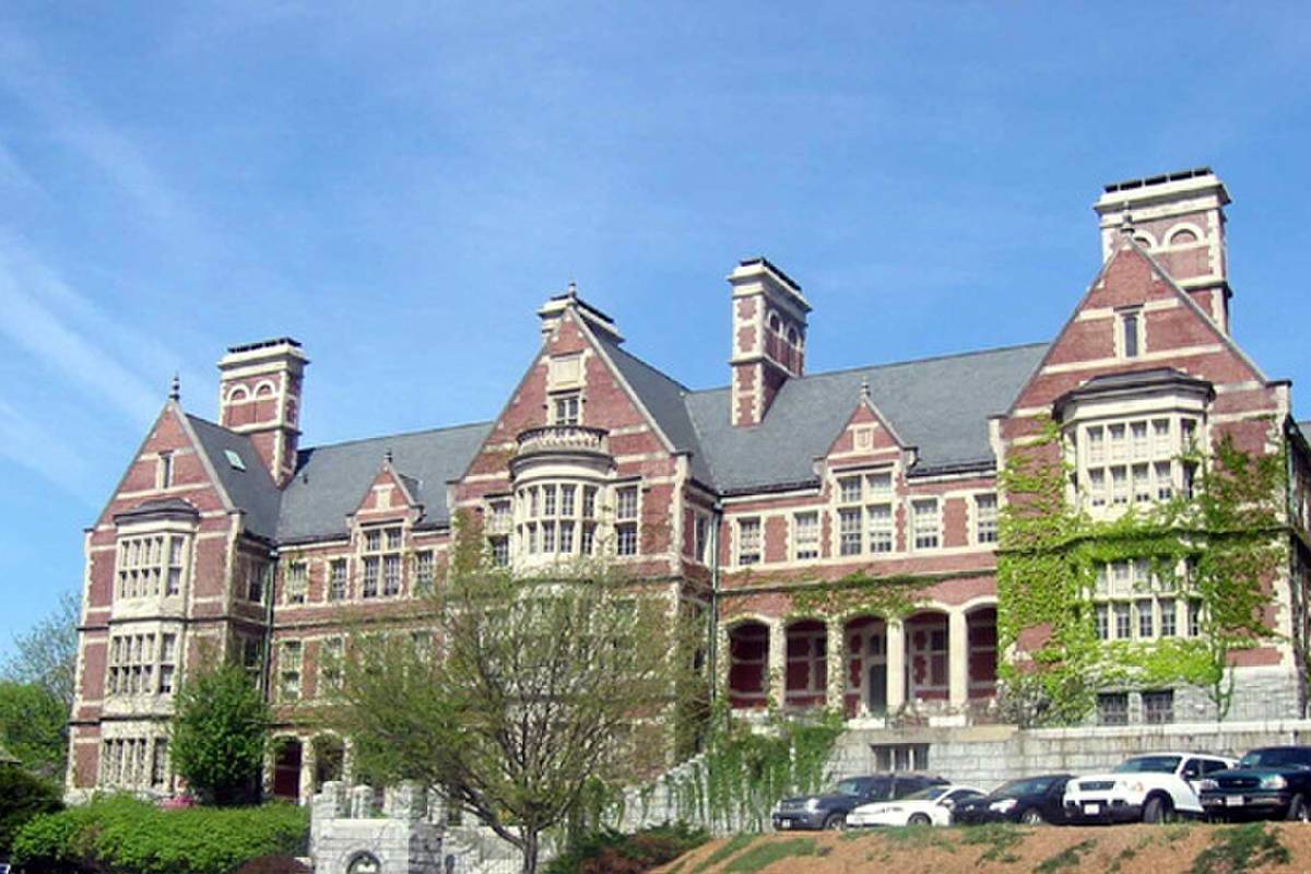 A large historic red brick and stone building with tall chimneys on a hill in Methuen MA
