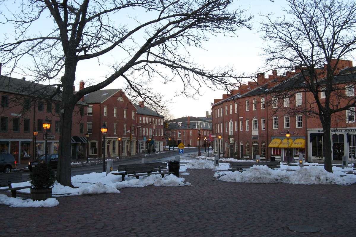 Brick buildings and glowing street lamps around Market Square on a winter evening in downtown Newburyport MA