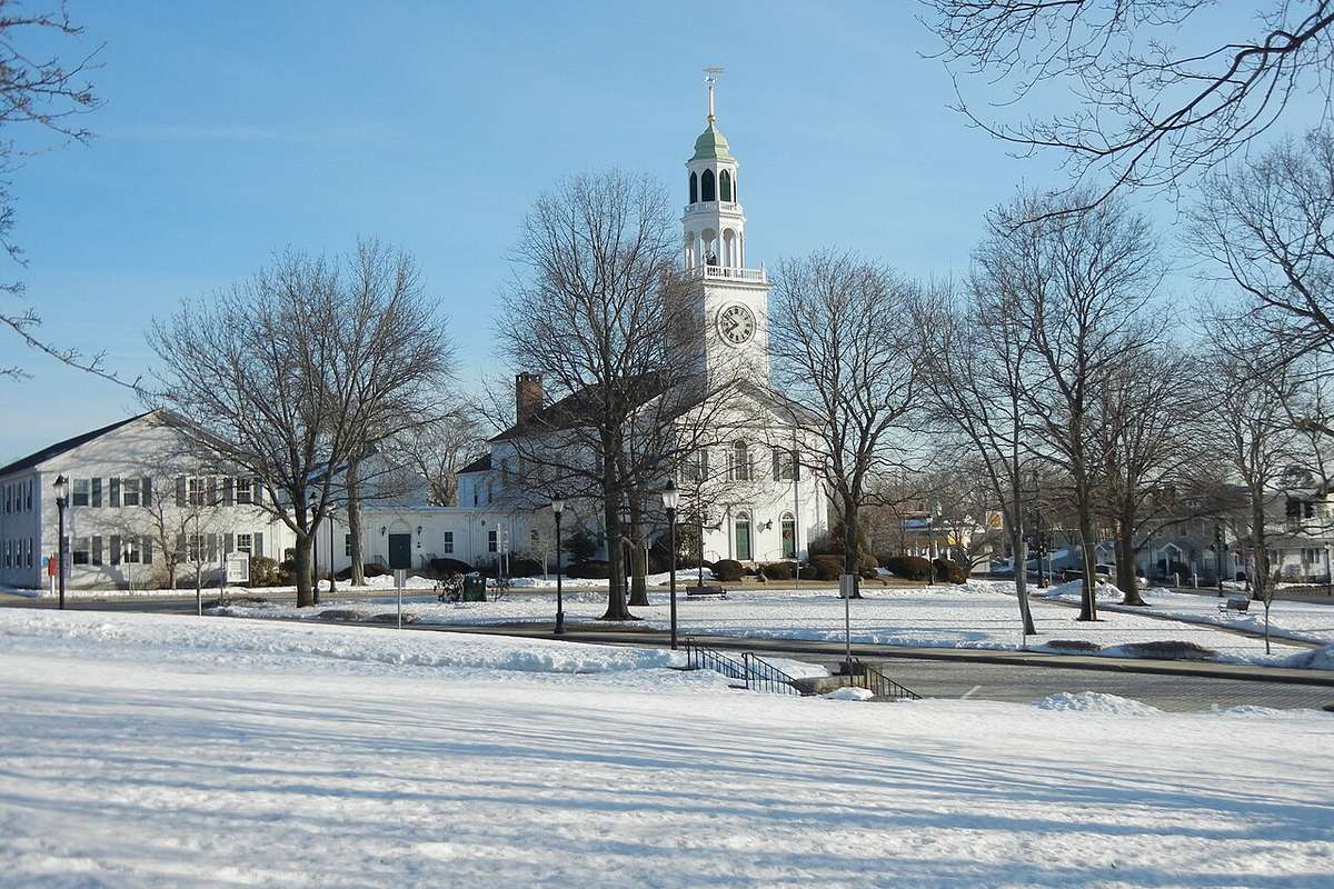 A white church steeple and the town common under fresh snow in Reading MA