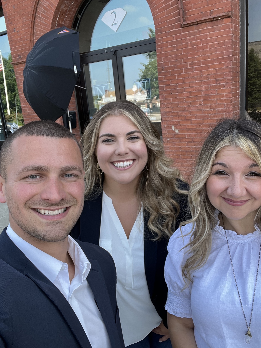 Adrianna Leone, Alex Greenwood, and Lisa Sevajian of the Lisa Sevajian Group standing together at a brick entrance