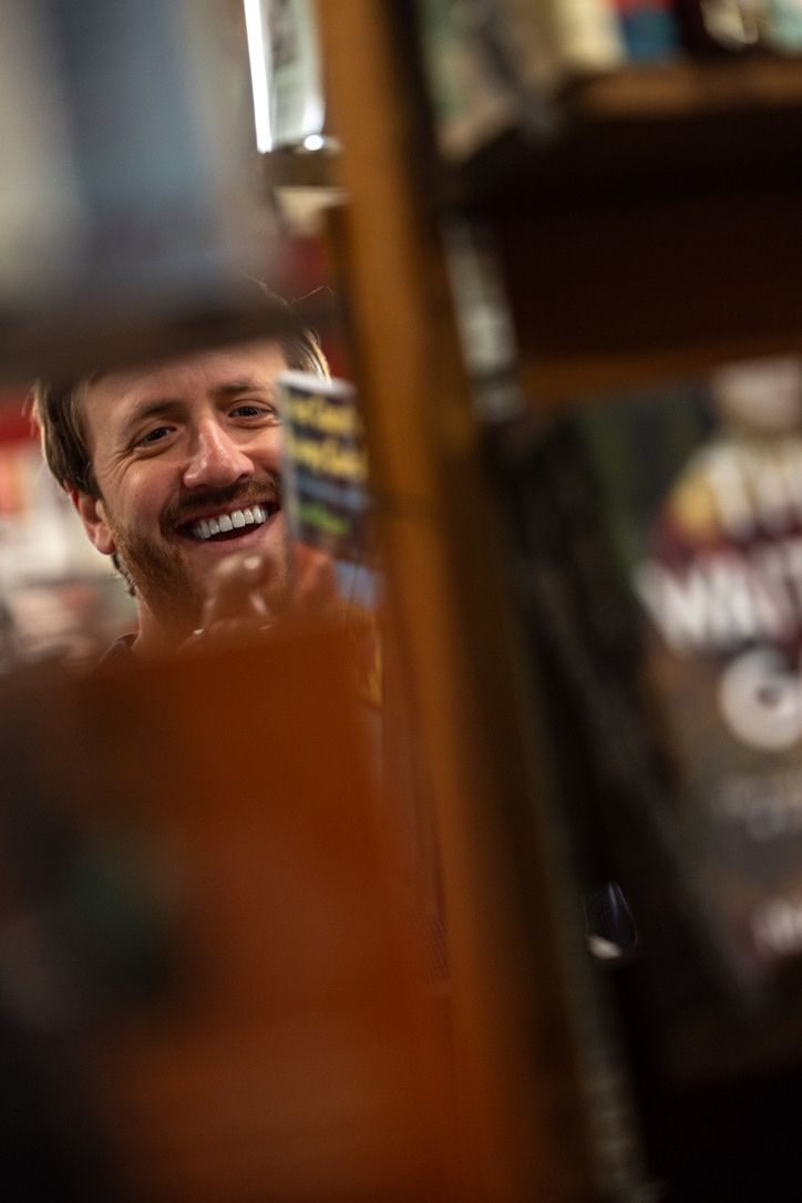 Steve Wallace smiling between the shelves at Jabberwocky Bookshop in Newburyport MA